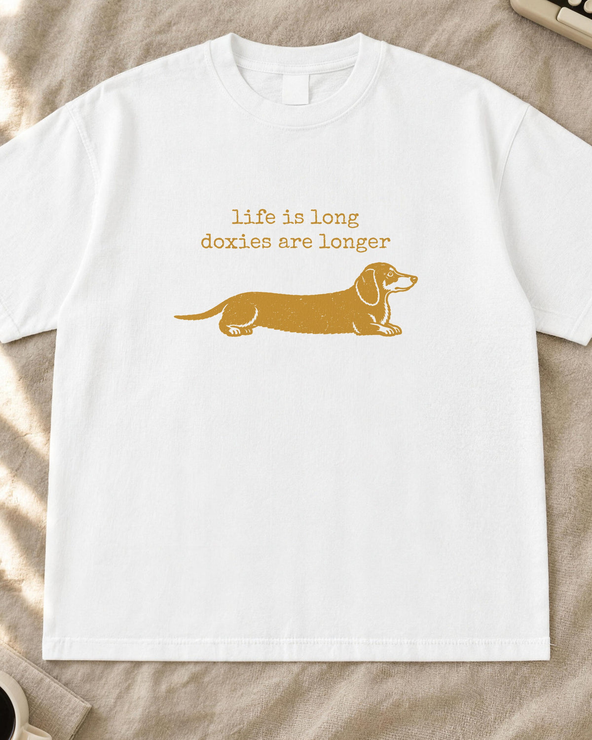 Dachshund shirt, life is long doxies are longer typewriter text with a stretched-out doxie stamp print in mustard on a white Comfort Colors tee