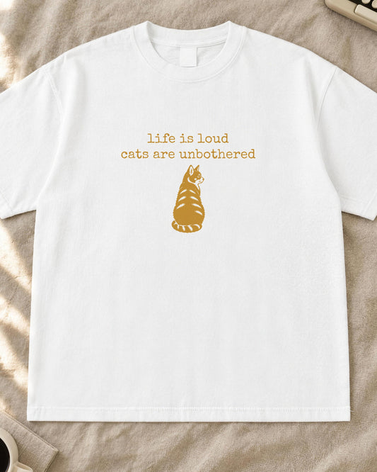 Cat shirt, life is loud cats are unbothered typewriter text with a cat sitting back-turned stamp print in mustard on a white Comfort Colors tee
